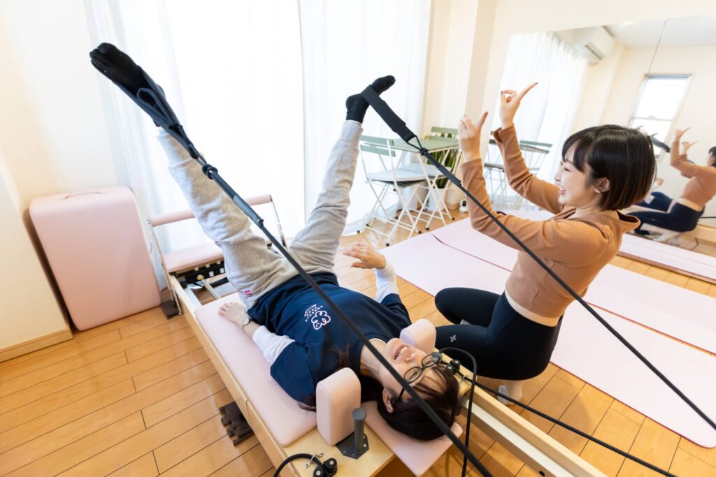 リフォーマーでストレッチする女性